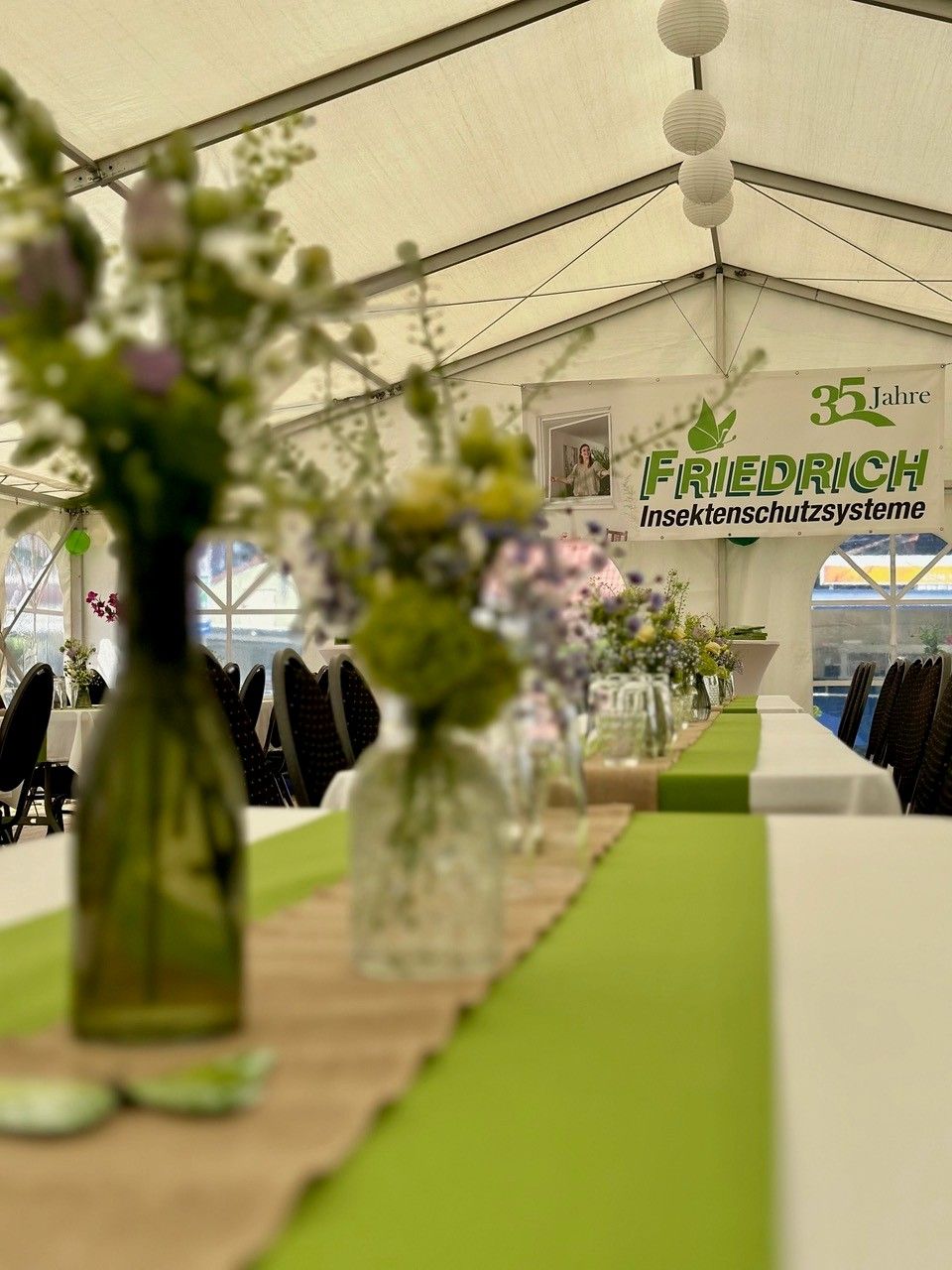 Eine Vase mit Blumen steht auf einem Tisch unter einem Zelt.