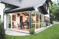 Ein Haus mit einer großen Veranda mit vielen Fenstern.