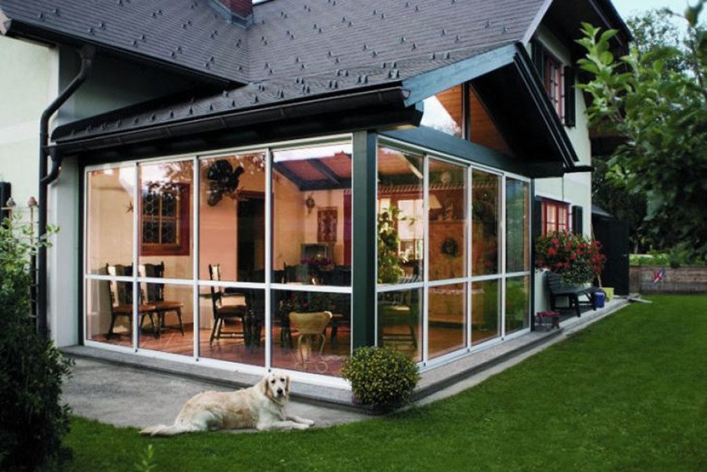 Ein Hund liegt vor einem Haus mit vielen Fenstern