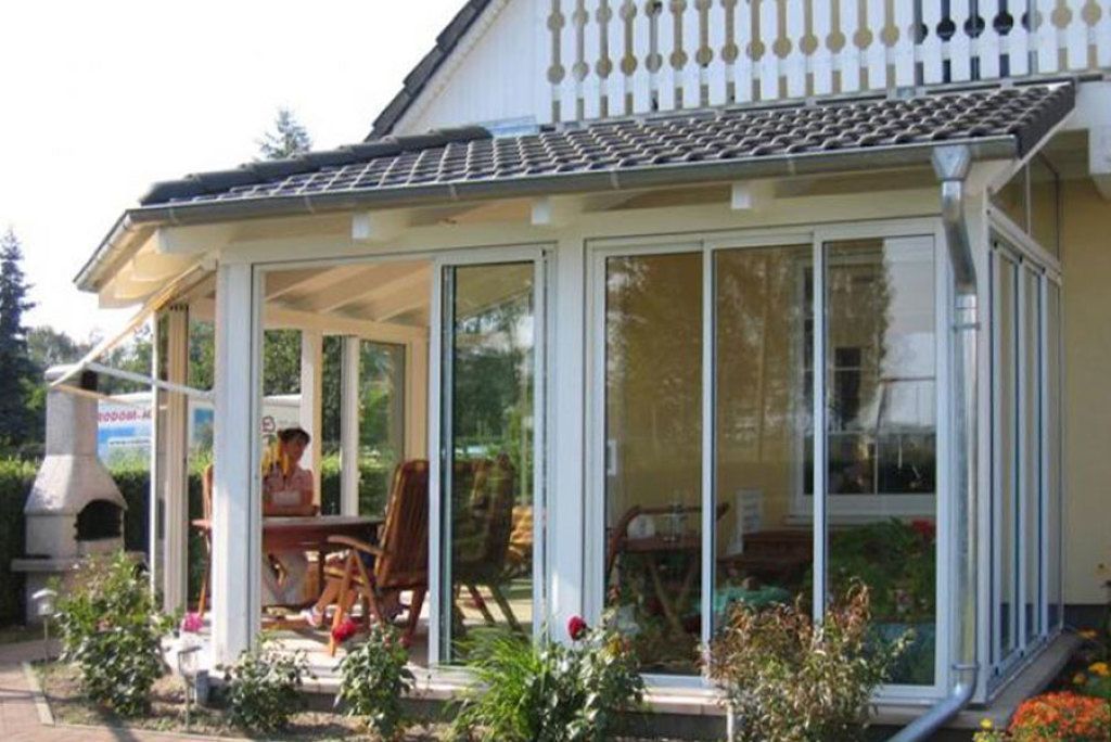 Eine Frau sitzt an einem Tisch auf der Veranda eines Hauses