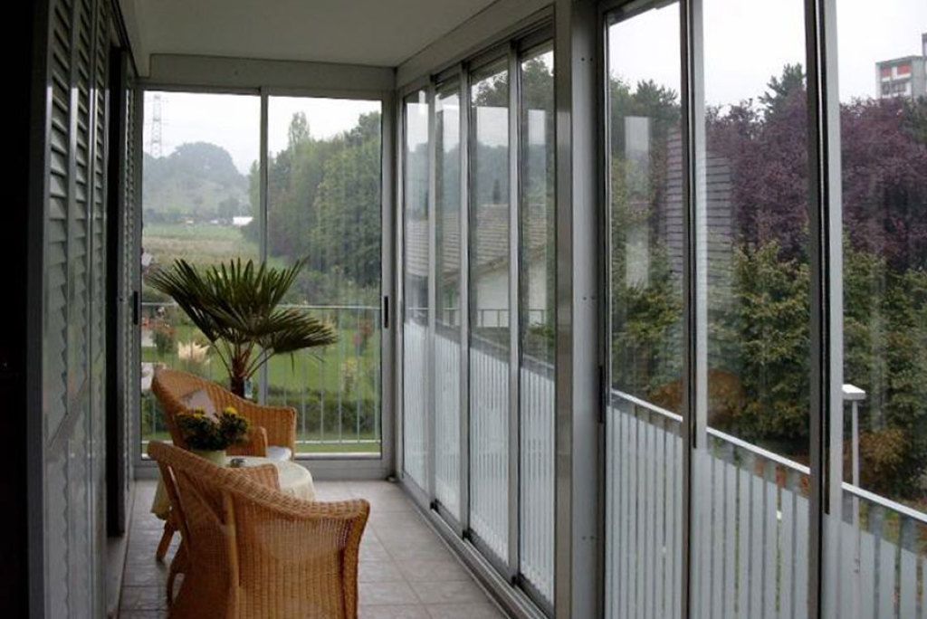 Ein großer Raum mit vielen Fenstern und Stühlen.