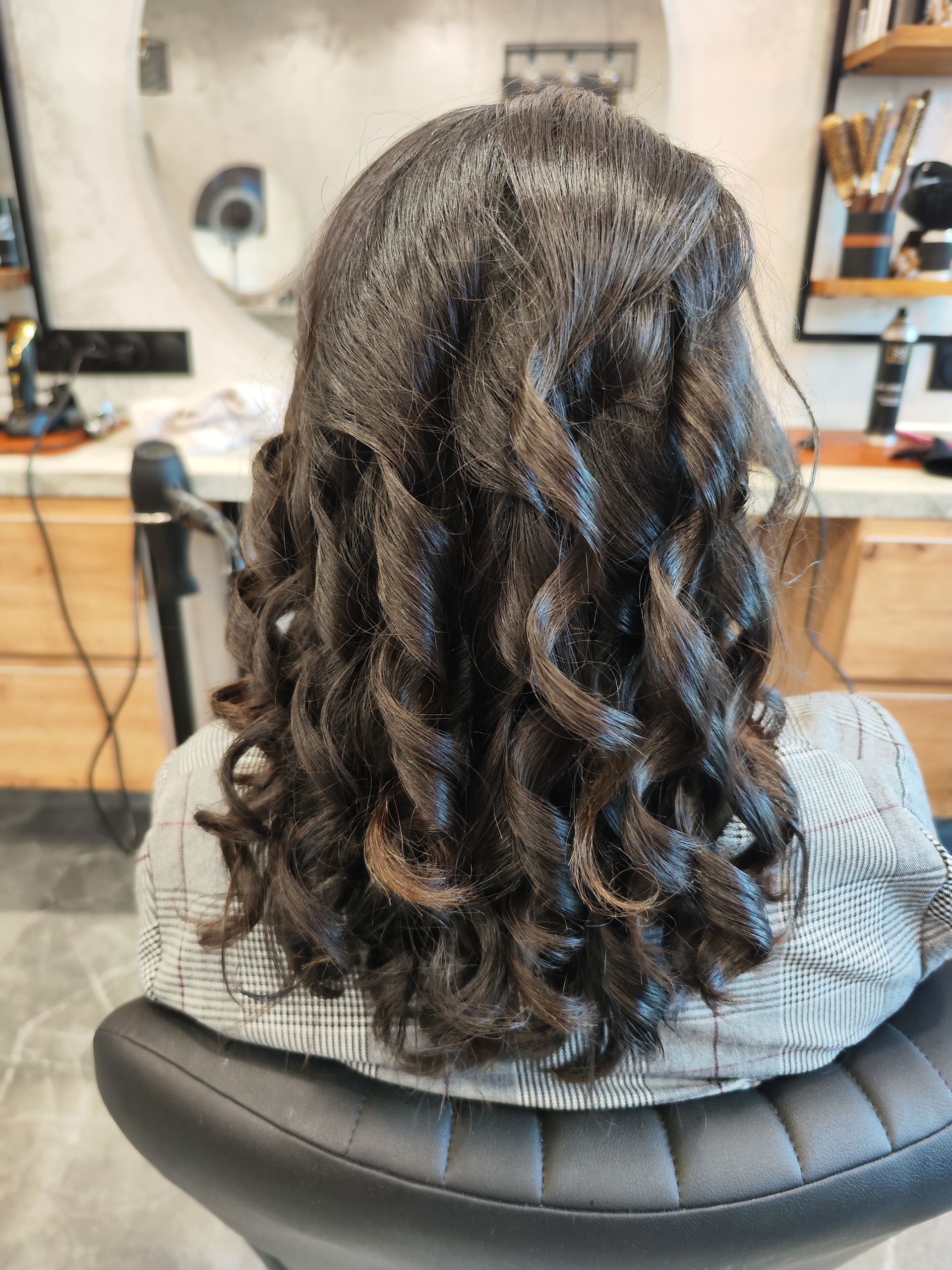 Femme aux cheveux noirs bouclés coiffée dans un salon.
