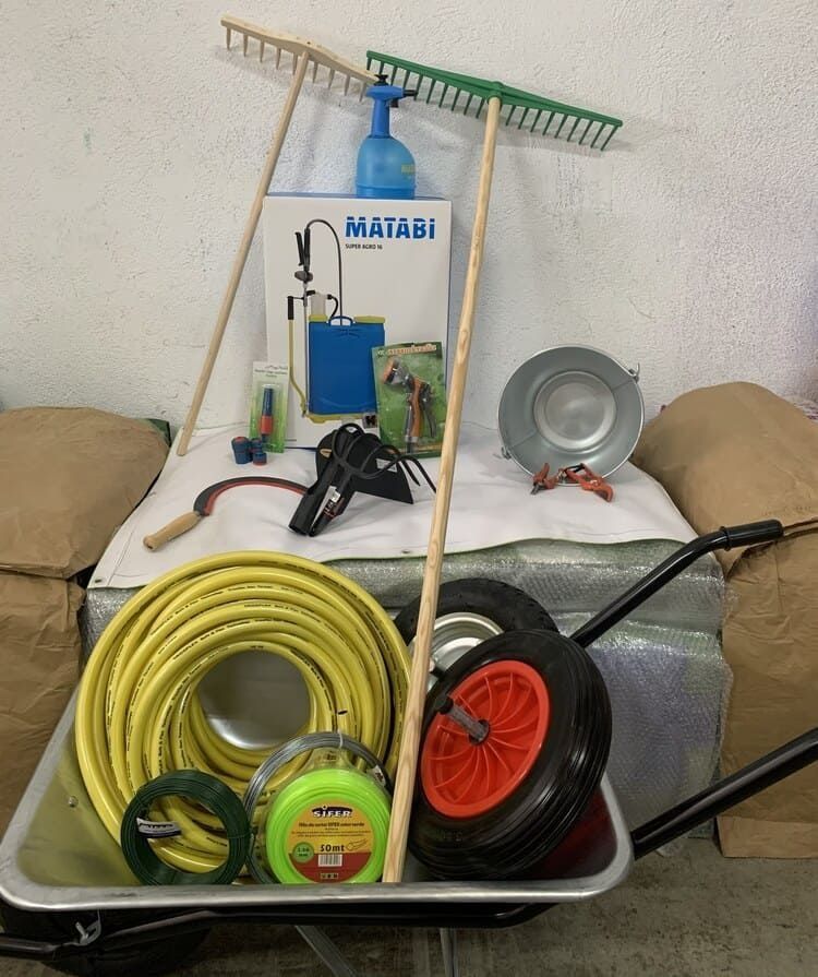 Una carretilla llena de herramientas de jardinería y una caja que dice matabi