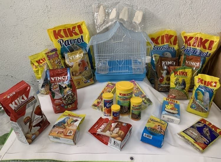 Una mesa llena de comida para loros Kiki y una jaula.
