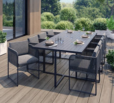 Collection Citadine. Table d'extérieur de couleur gris anthracite avec 8 fauteuils coordonnés de la même couleur sur une terrasse en bois.