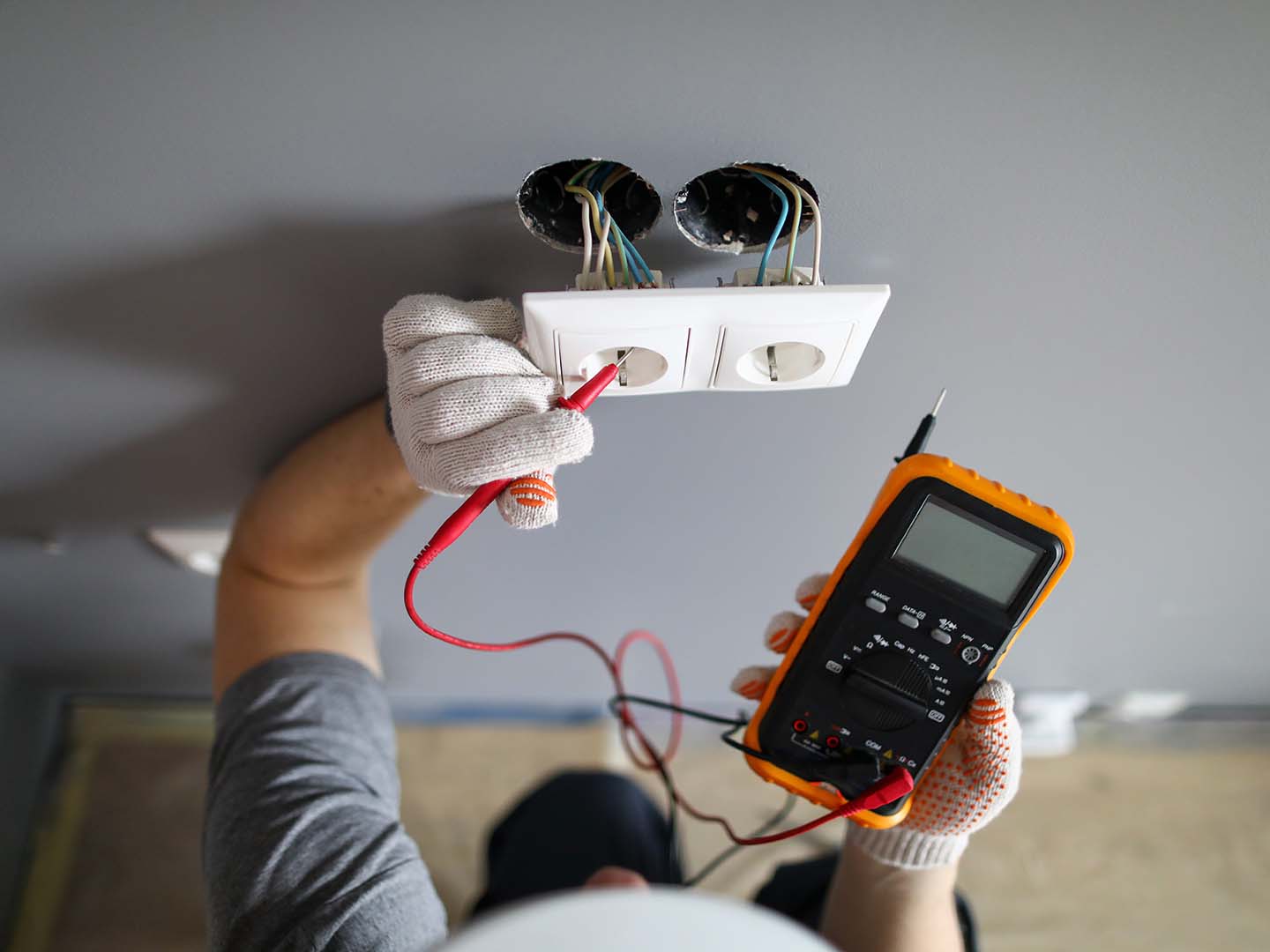 Un électricien contrôle une prise avec un voltmètre