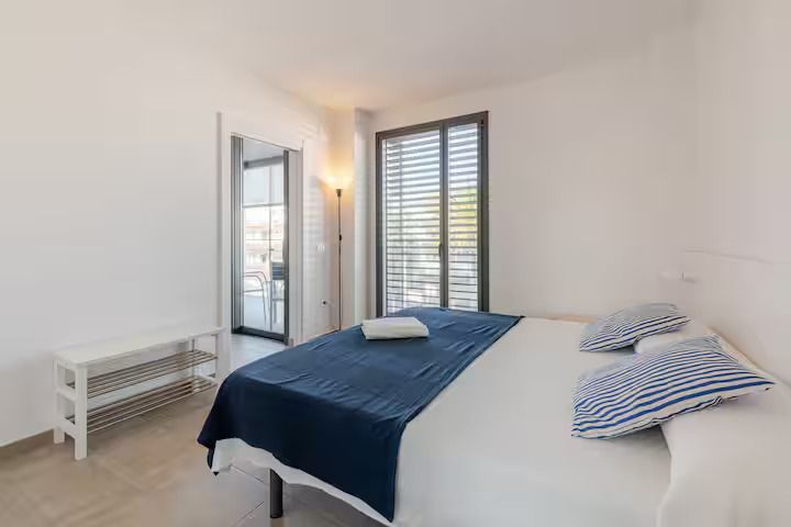 Un dormitorio con cama, espejo y ventana.