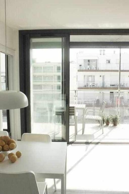 Un comedor con mesa y sillas y una puerta corrediza de vidrio que conduce a un balcón.