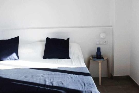 Un dormitorio con una cama y una mesita de noche con un jarrón encima.