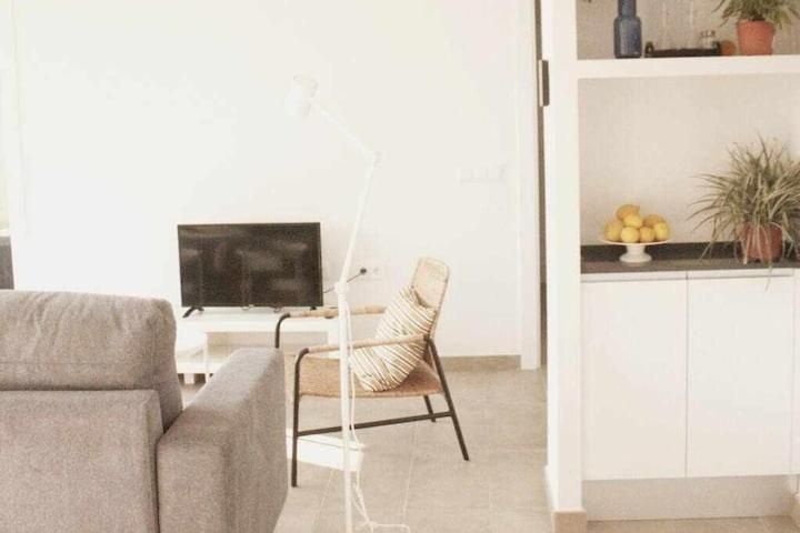 Una sala de estar con un sofá, una silla, una televisión y una lámpara.