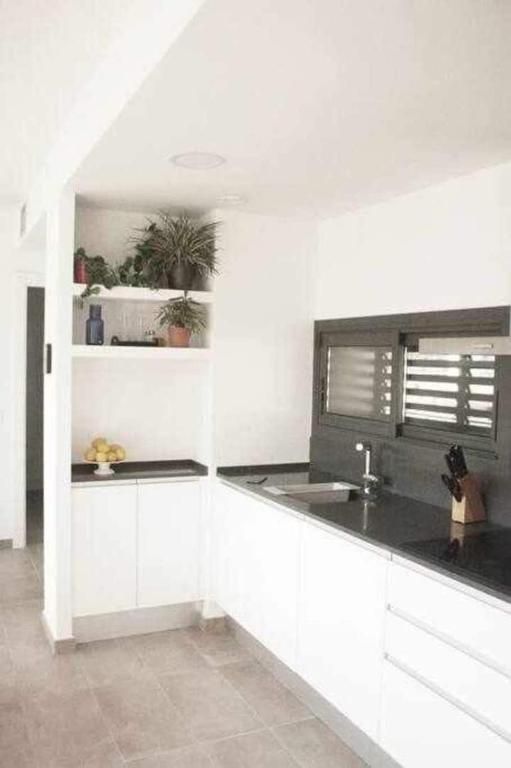 Una cocina con gabinetes blancos, encimeras negras, un fregadero y una ventana.