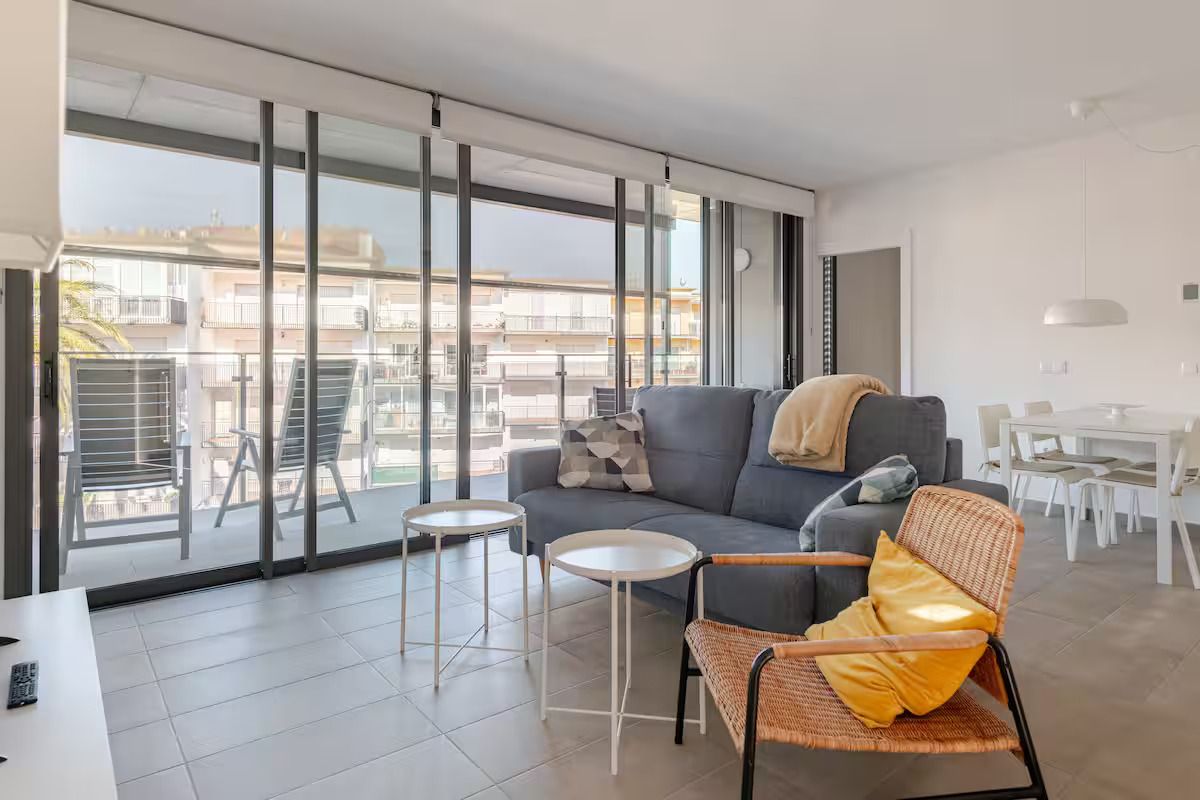 Una sala de estar con sofá, silla, mesas y un balcón.