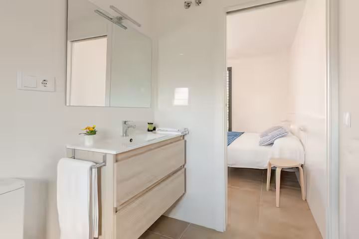 Un baño con lavabo y espejo al lado de un dormitorio.