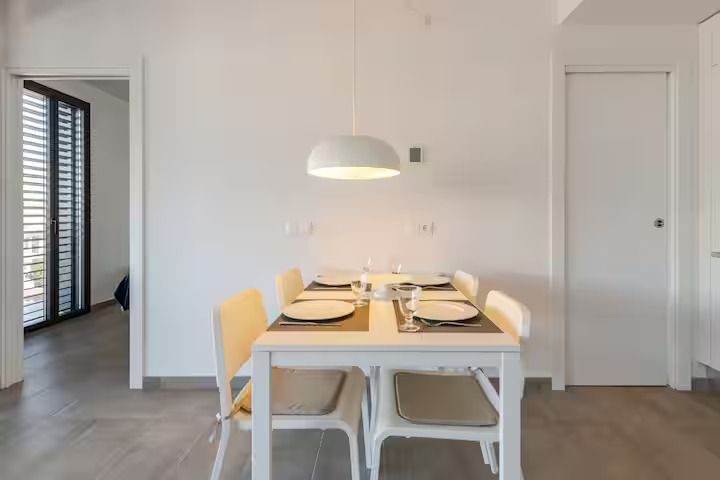 Un comedor con una mesa y sillas y platos encima.