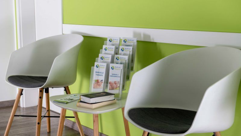 Im Wartezimmer gibt es zwei Stühle und einen Tisch.