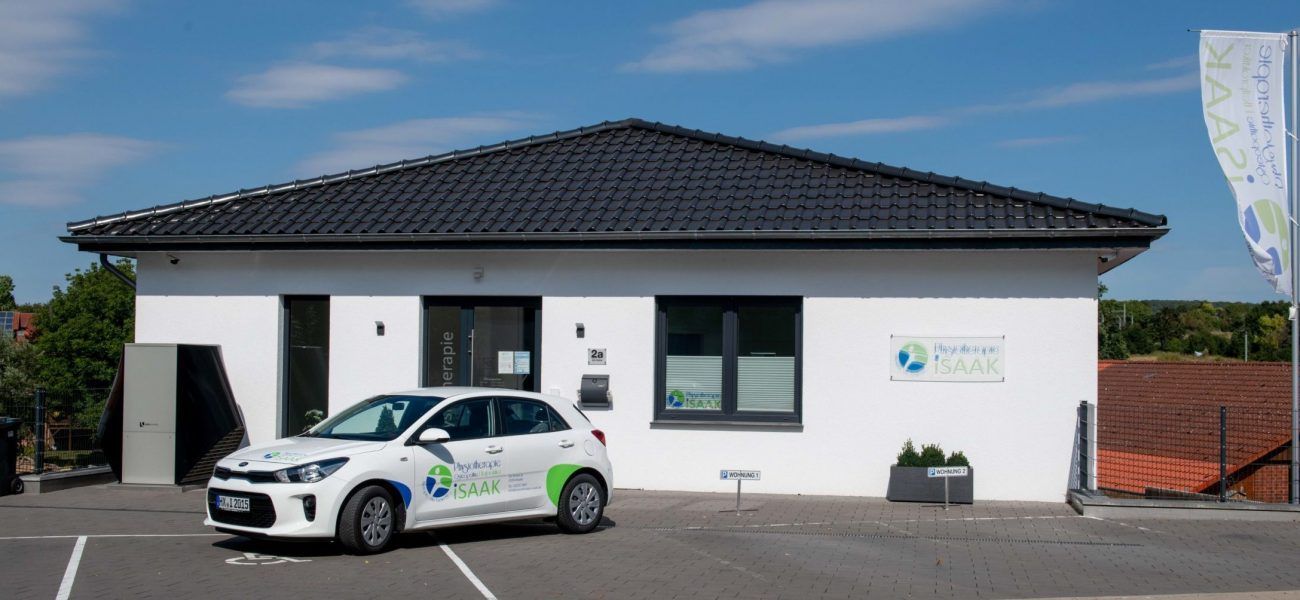 Ein weißes Auto parkt vor einem weißen Gebäude.