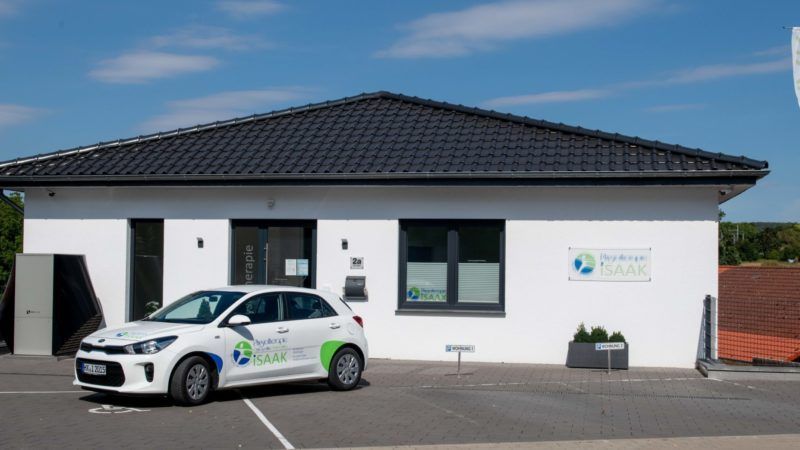 Ein weißes Auto parkt vor einem weißen Gebäude.