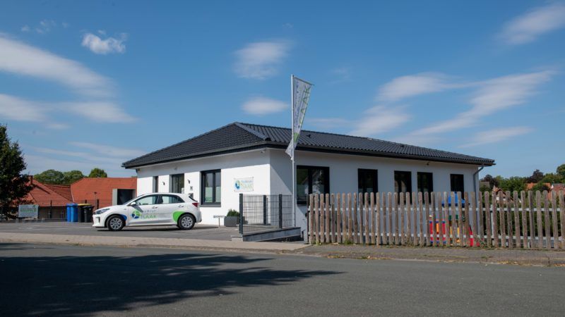 Ein weißes Auto parkt vor einem weißen Haus.