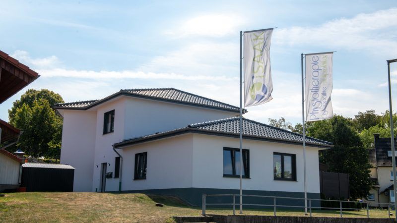 Ein weißes Haus mit drei wehenden Flaggen davor