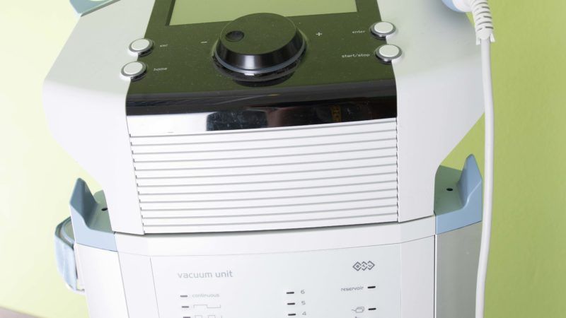 Auf einem Tisch steht eine weiß-schwarze Maschine mit einem daran befestigten Kabel.