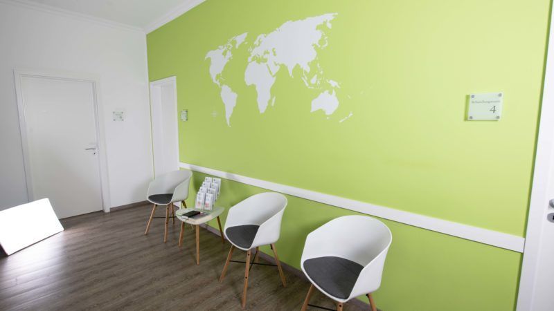 Ein Wartezimmer mit Stühlen und einer Weltkarte an der Wand.
