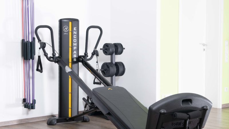 Ein Fitnessstudio mit einer Bank, Hanteln und Widerstandsbändern.