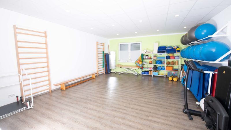 Eine große leere Turnhalle mit vielen Geräten auf dem Boden.