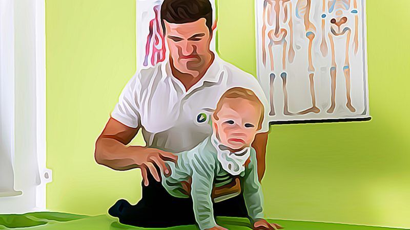 Ein Mann hält ein Baby, das auf einem grünen Tisch krabbelt.