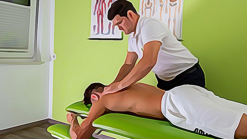 Ein Mann liegt auf einem Tisch und wird von einem Masseur massiert.