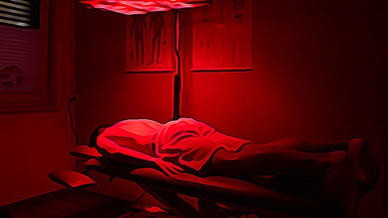 Eine Person liegt unter einem roten Licht auf einem Bett.