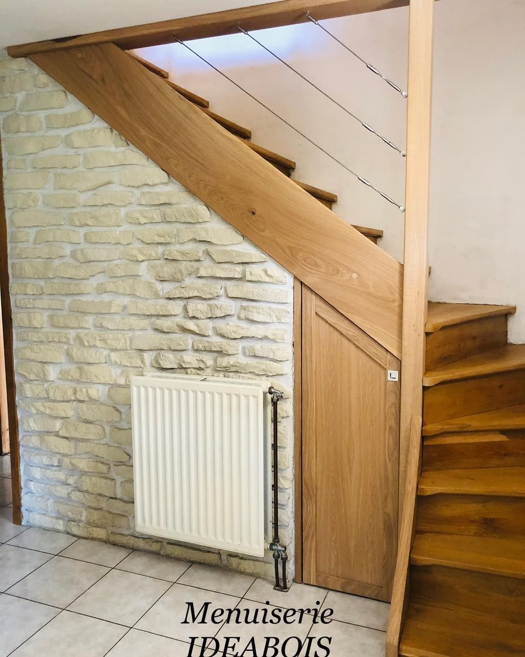 Escalier en bois avec mur en pierre, rangements intégrés et radiateur.