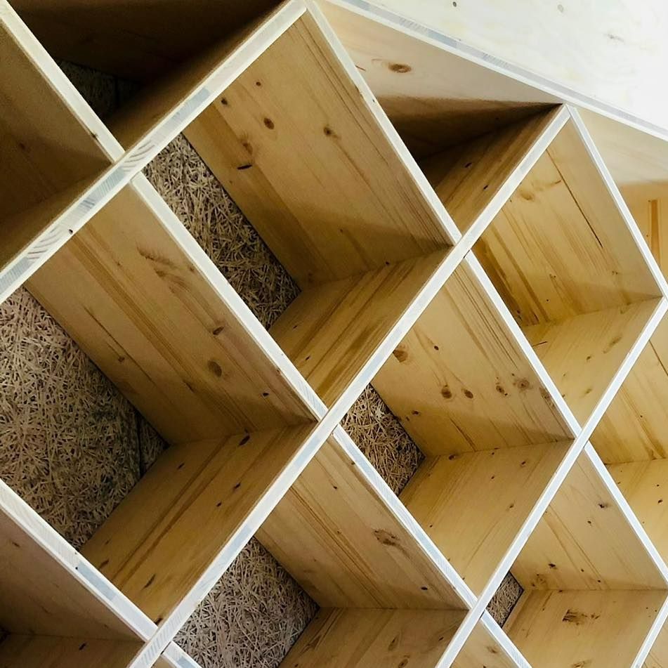 Étagère en bois à compartiments en forme de losange, sur fond texturé brun clair.