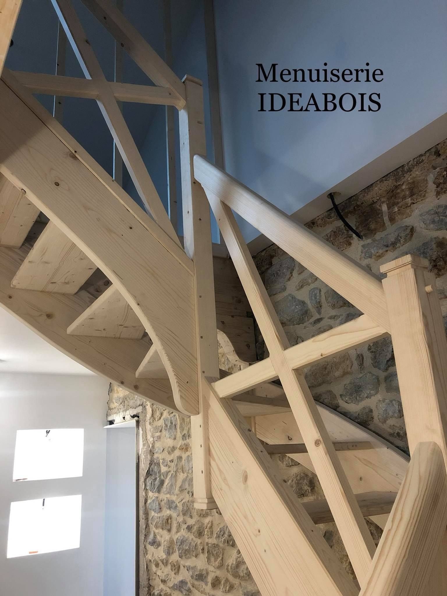 Escalier en bois avec rampe, contre un mur en pierre. 