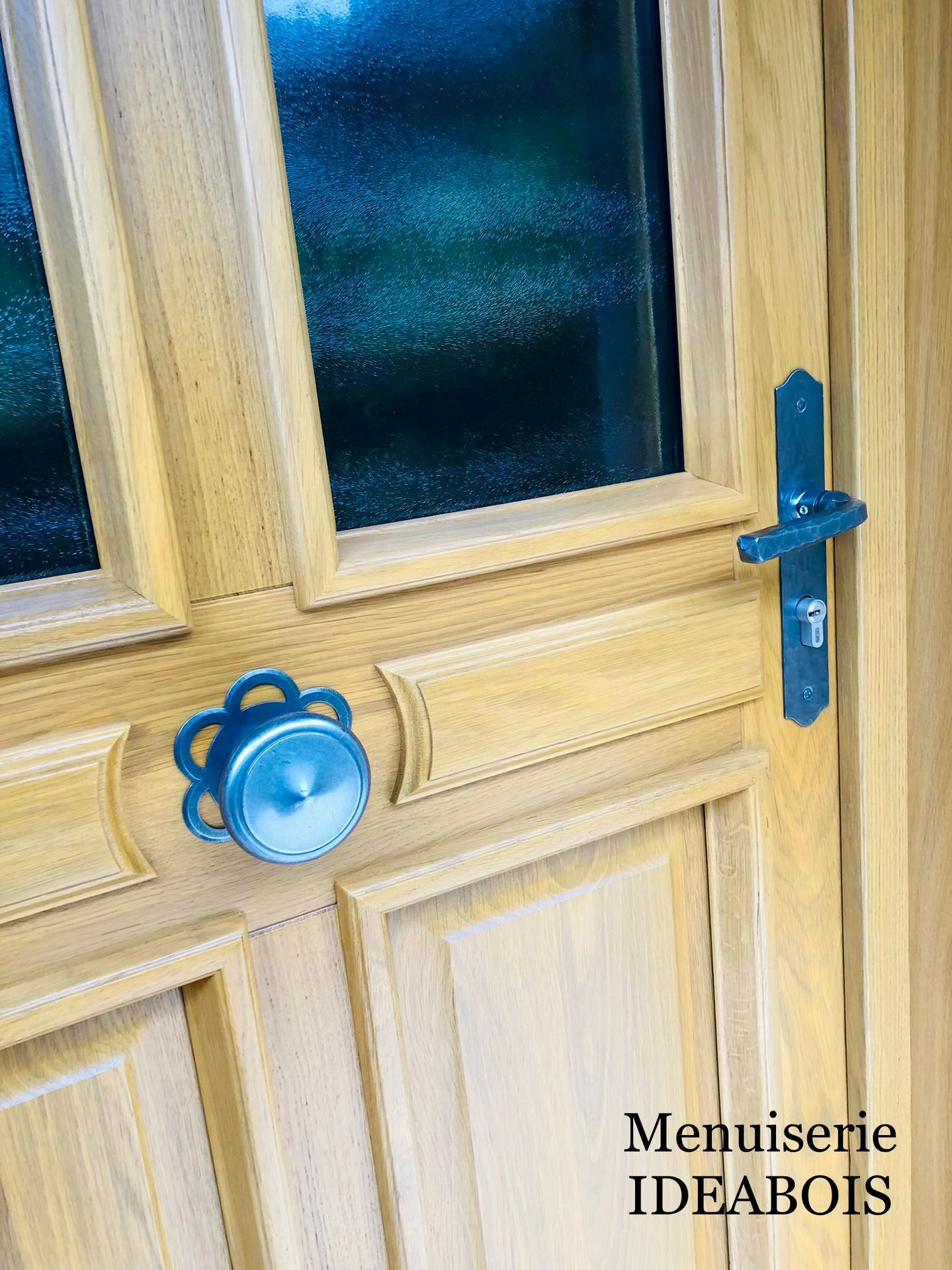 Porte en bois avec panneau de verre, poignée en métal bleu et bouton décoratif.