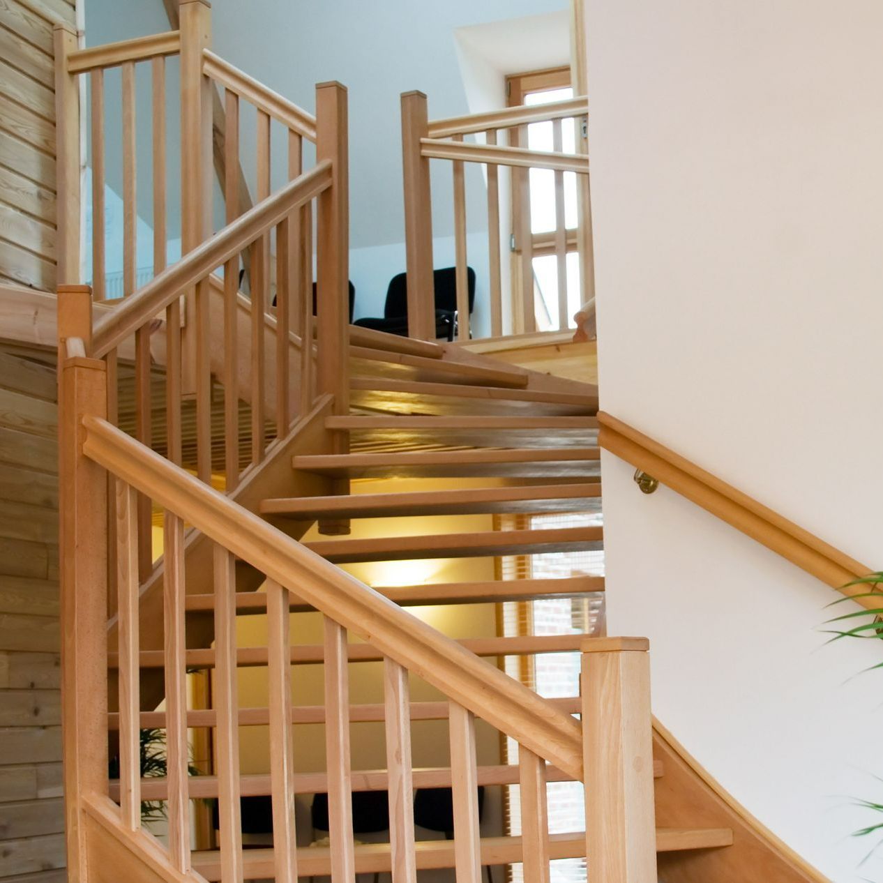 Escalier en bois avec rampe et balustres dans un intérieur lumineux.