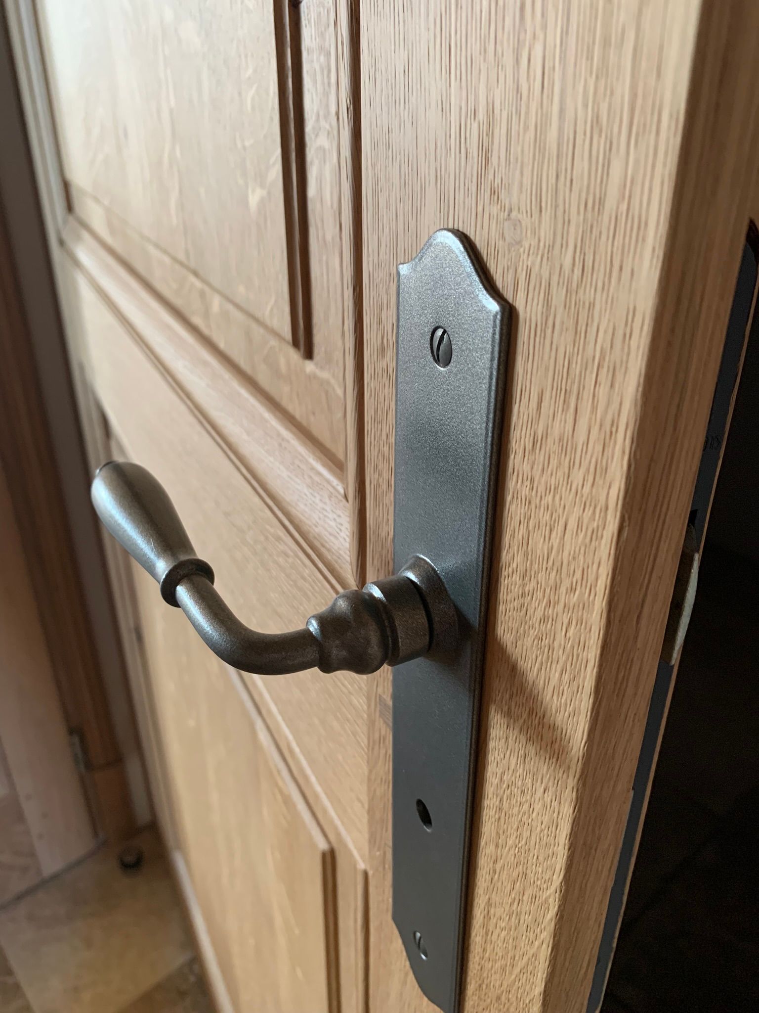 Porte en bois avec panneaux de verre et poignée, posée sur une surface en bois.