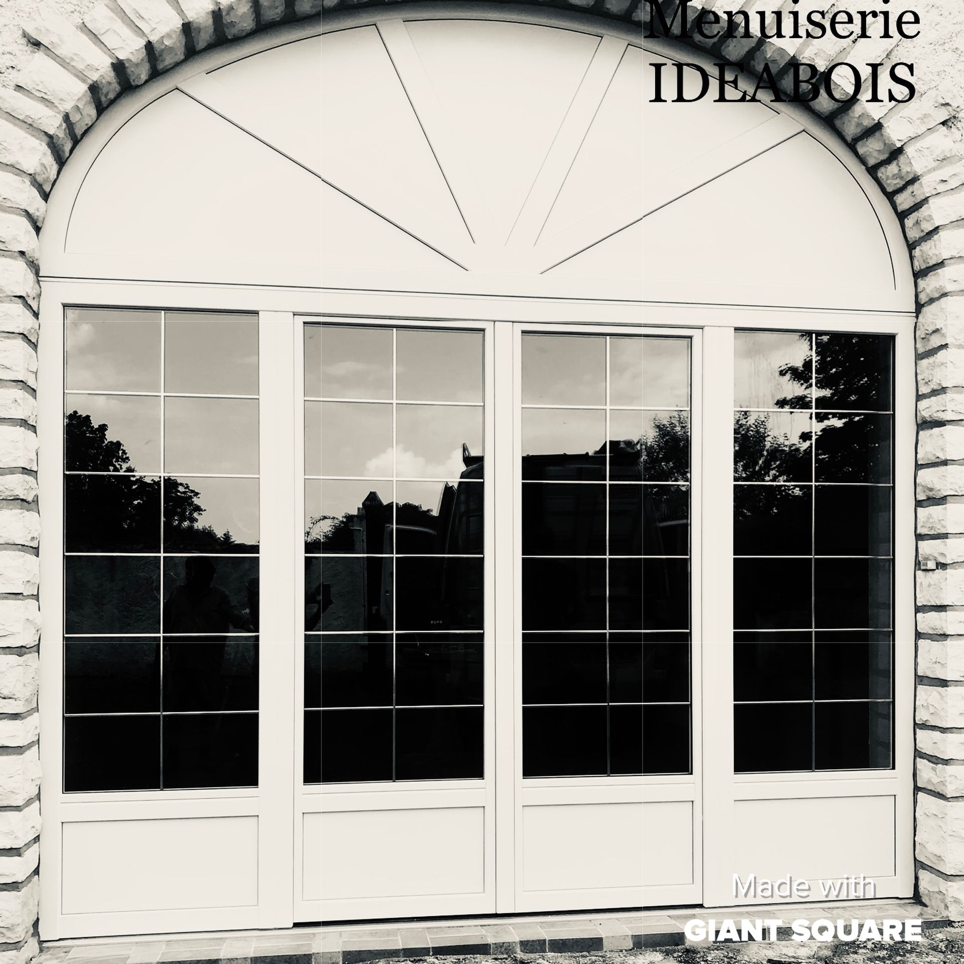 Fenêtres cintrées blanches à petits carreaux, encadrées par une arche en pierre. 