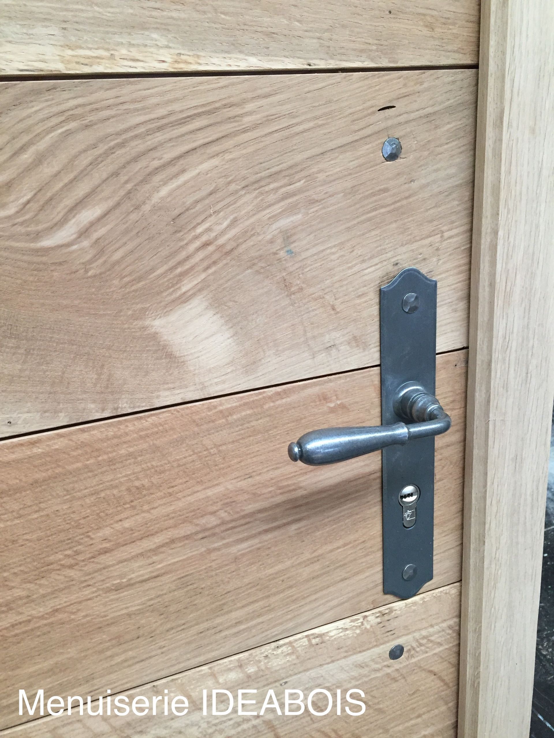 Porte en bois avec une poignée en métal foncé et une serrure.