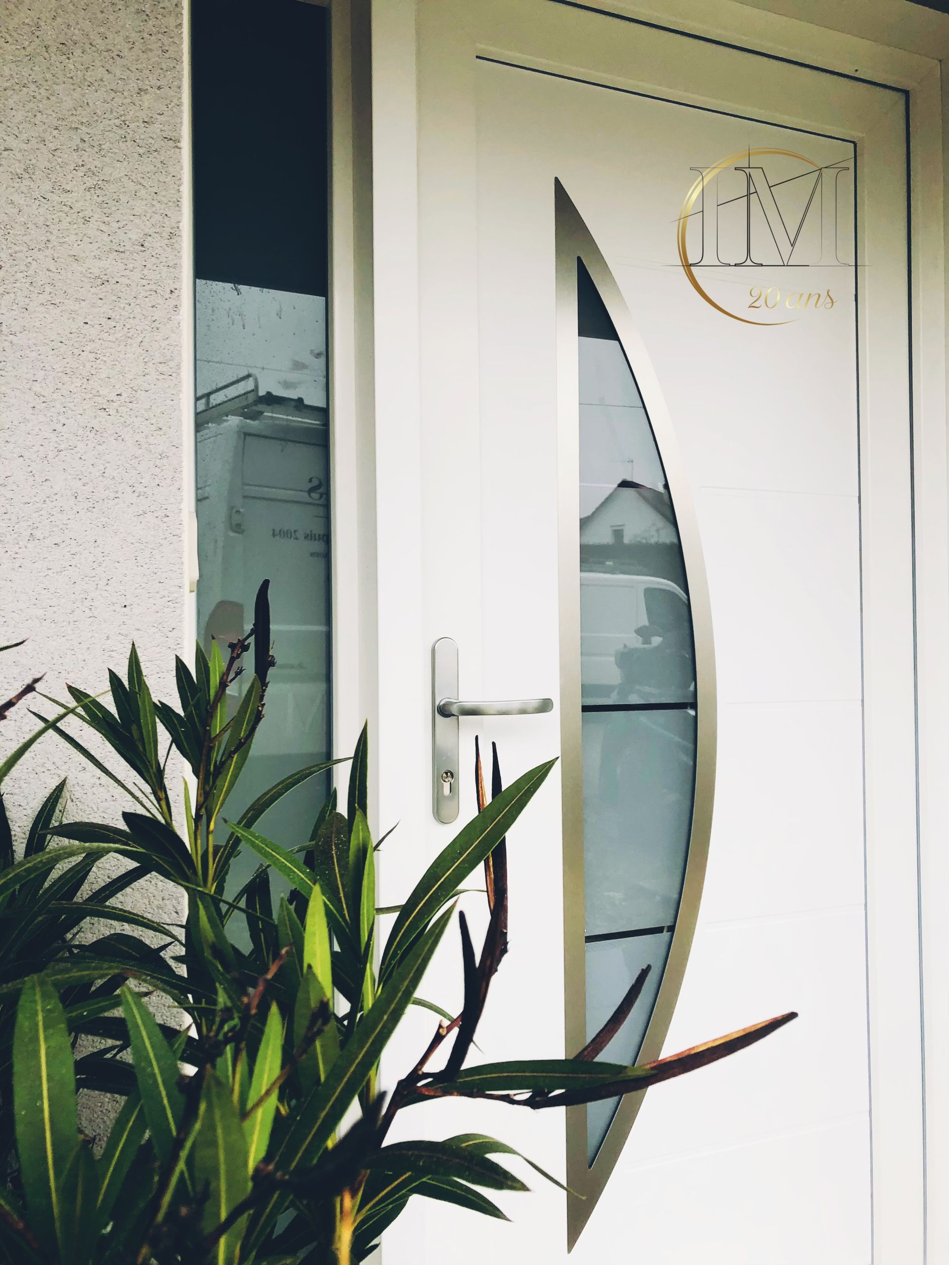 Porte d'entrée blanche avec insert en verre ovale et poignée argentée, à côté d'une fenêtre latérale.