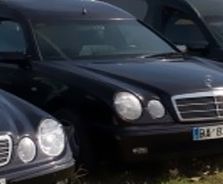 Una fila de coches negros están aparcados uno al lado del otro en el césped.