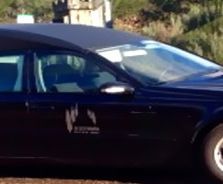 Un coche negro con techo negro está estacionado al costado de la carretera.