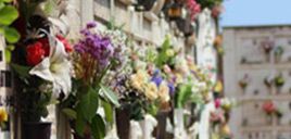 Un ramo de flores cuelga en una pared en un cementerio.