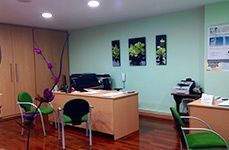 Una habitación con un escritorio, sillas y una impresora.