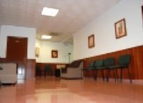 Un largo pasillo con sillas y un sofá en la sala de espera de un hospital.