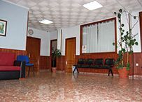 Una sala de espera con un sofá, sillas y una planta en maceta.