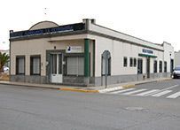 Un edificio blanco con techo verde está en la esquina de una calle.