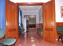 Un pasillo con sillas y puertas abiertas que conducen a una habitación.