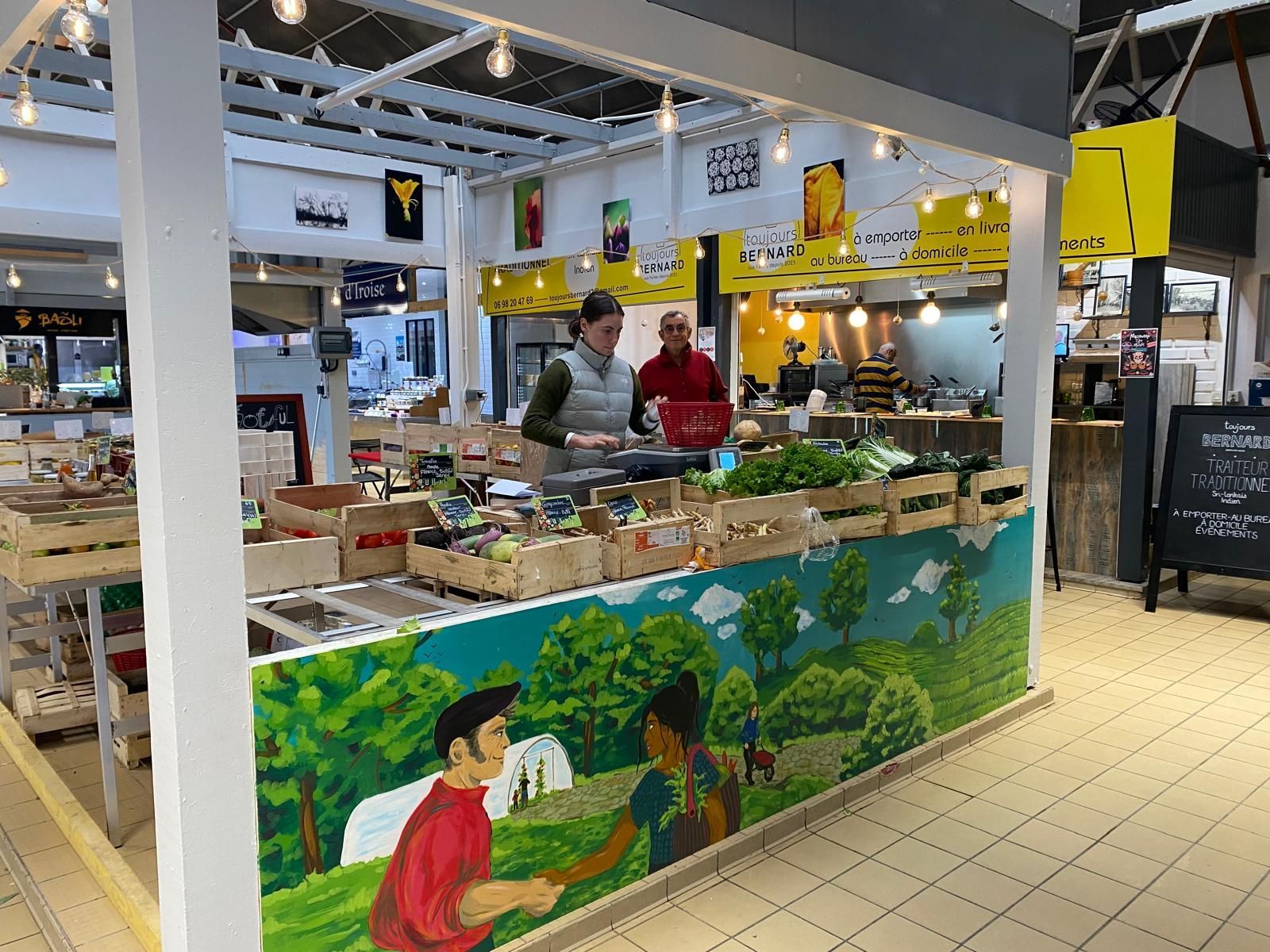 Légumes exposés sur un marché de producteurs locaux, notamment des carottes, des concombres et des légumes verts.