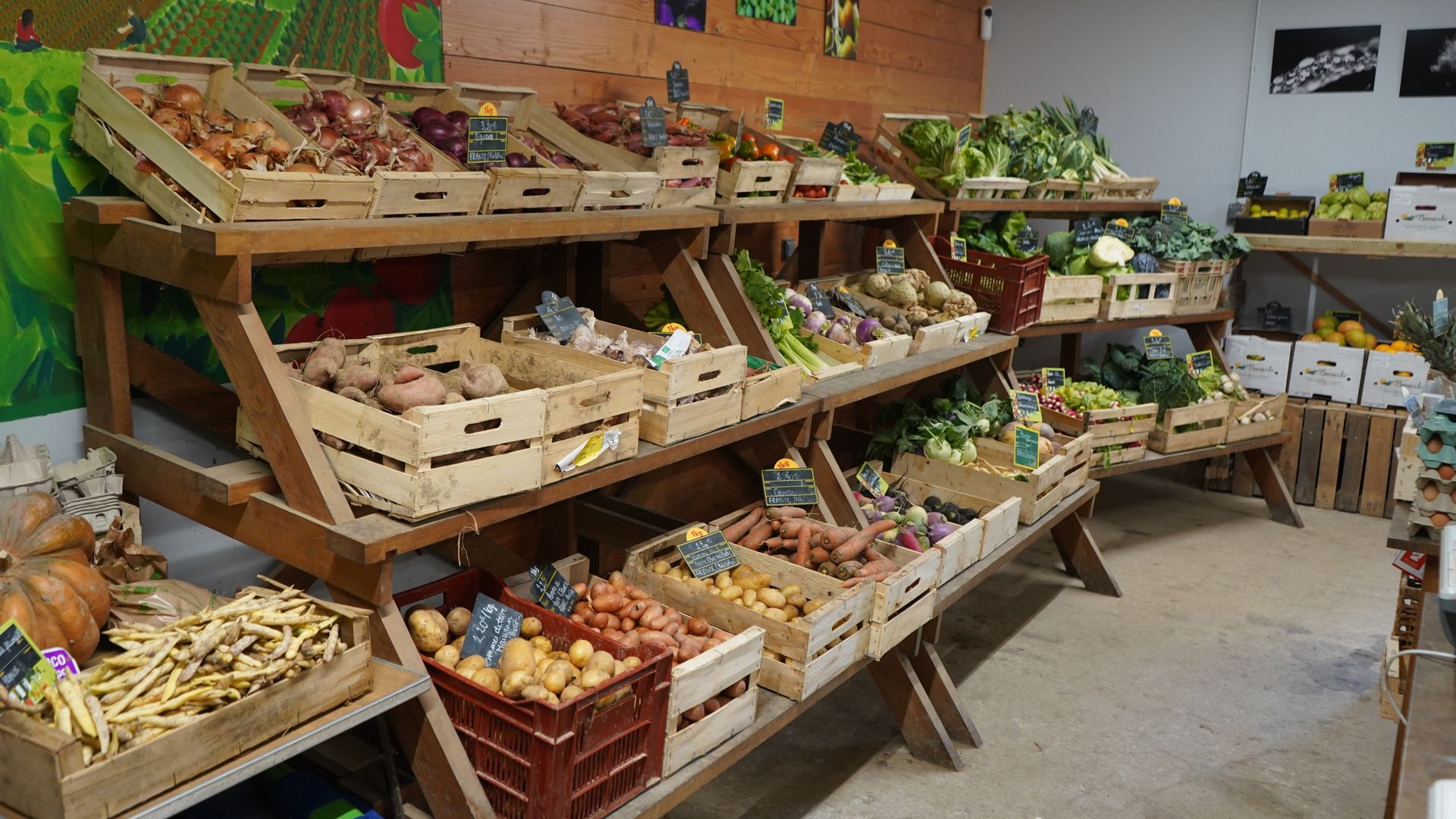 Des pots de confiture dans des paniers tressés sur un étal de marché, à côté de fruits frais.