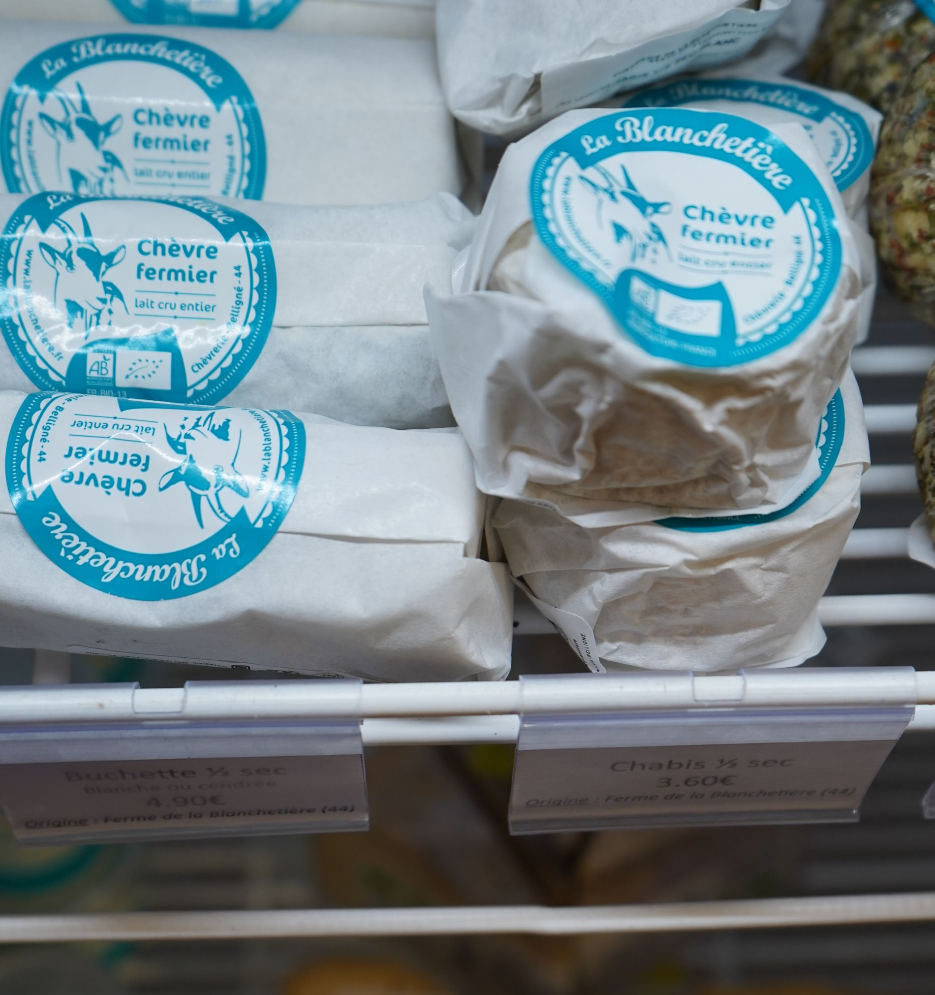 Différents fromages disposés sur une surface en bois avec des figues, des myrtilles et des noix.